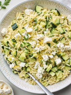 close up of lemon orzo pasta salad with cucumber, feta, and fresh herbs.