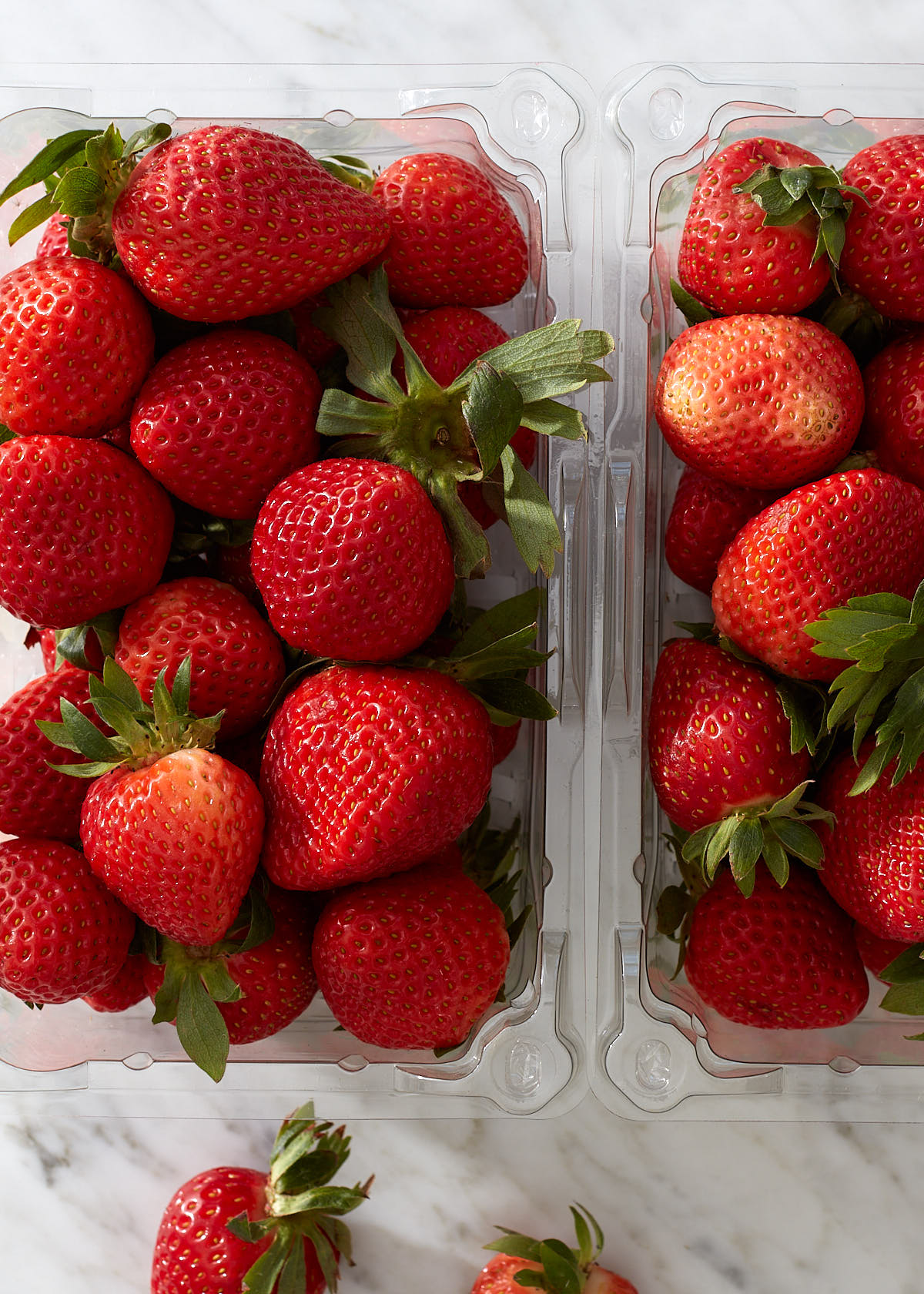 Close up of fresh strawberries in clear store containers.
