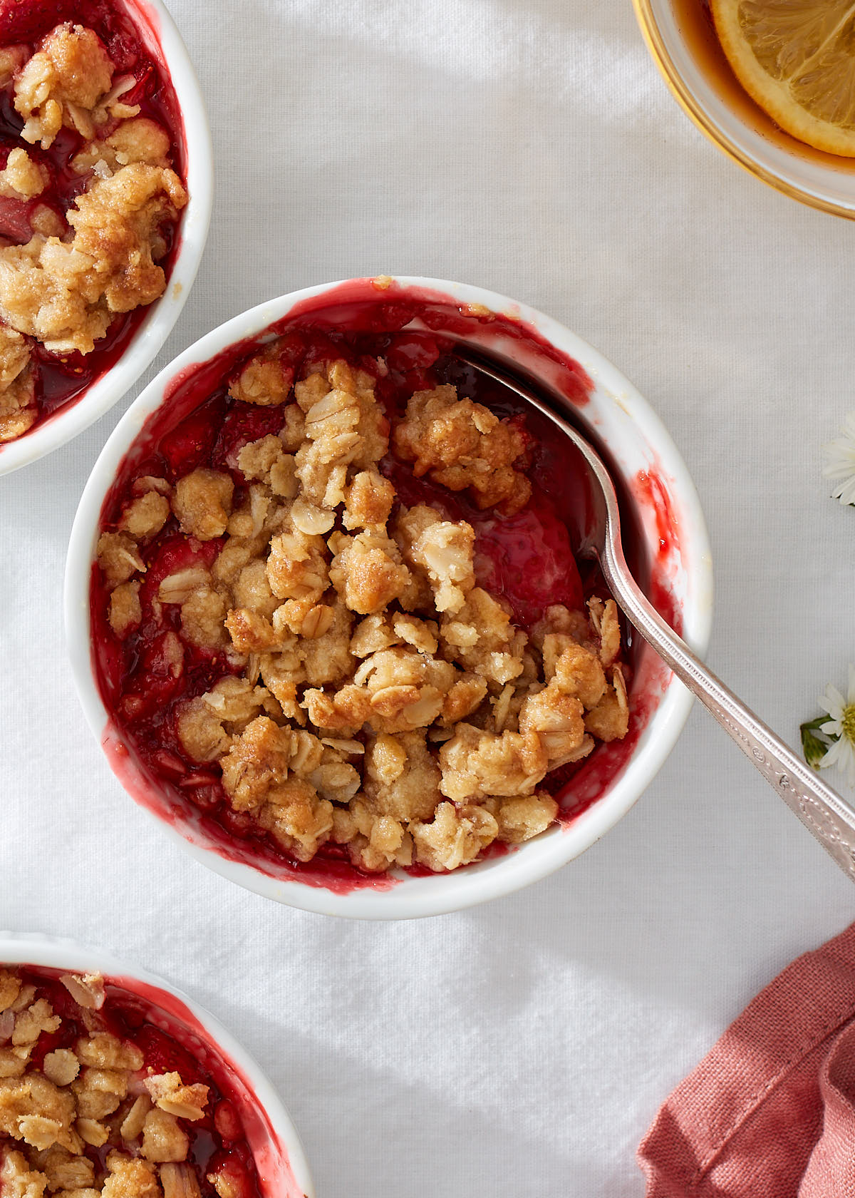 Close up of an invididual strawberry oat crisp with a vintage silver spoon.