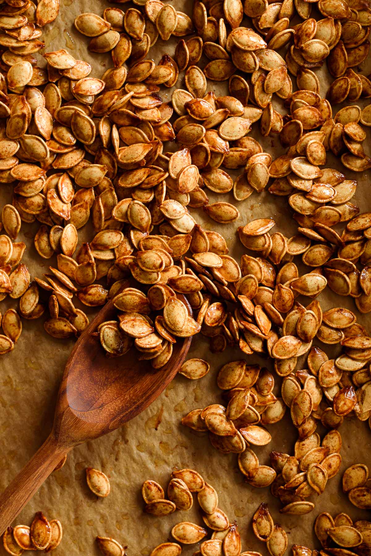 Roasted pumpkin seeds with brown sugar, butter, cinnamon, and salt on parchment paper.