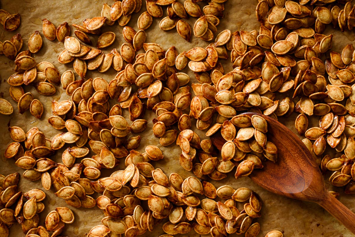 Roasted pumpkin seeds with brown sugar, butter, cinnamon, and salt on parchment paper.