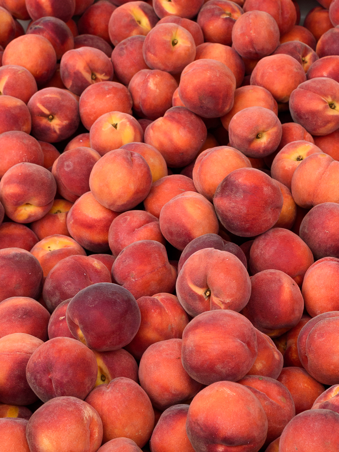 Fresh, ripe yellow peaches stacked in a farmers market bin | via forkknifeswoon.com @forkknifeswoon