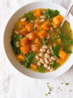 A bowl of white bean and butternut squash soup with kale.