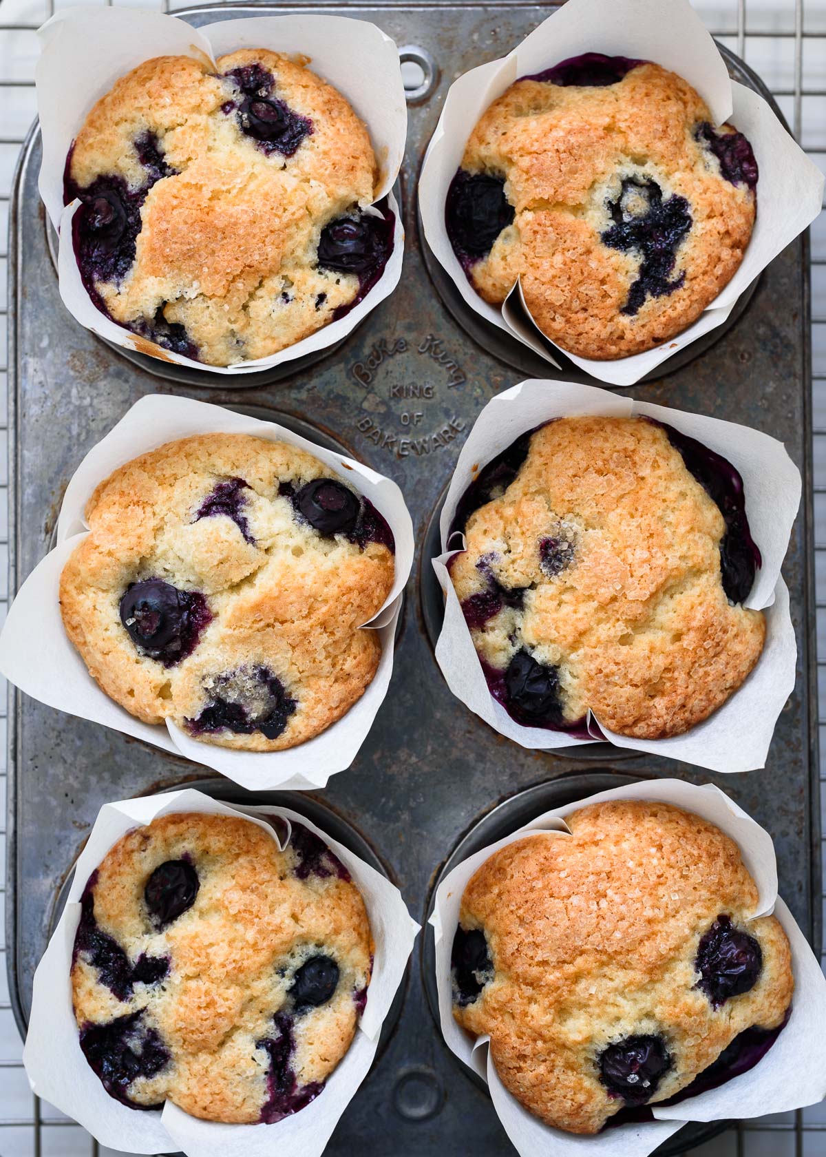 Lemon blueberry muffins with white tulip liners in a vintage muffin tin.