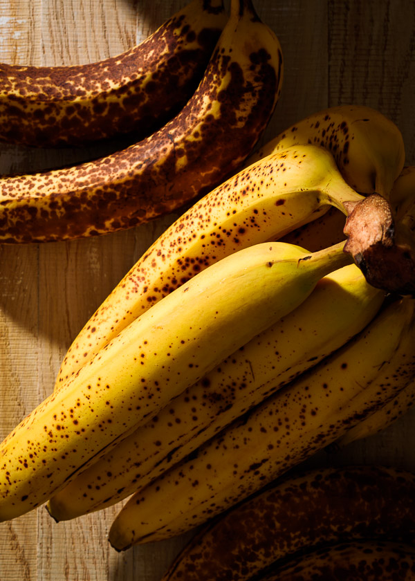 Spotty, ripe bananas on a wood background.