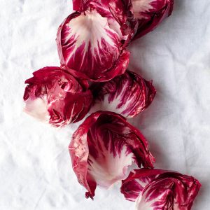 Fresh red and white radicchio leaves on a white linen tablecloth.