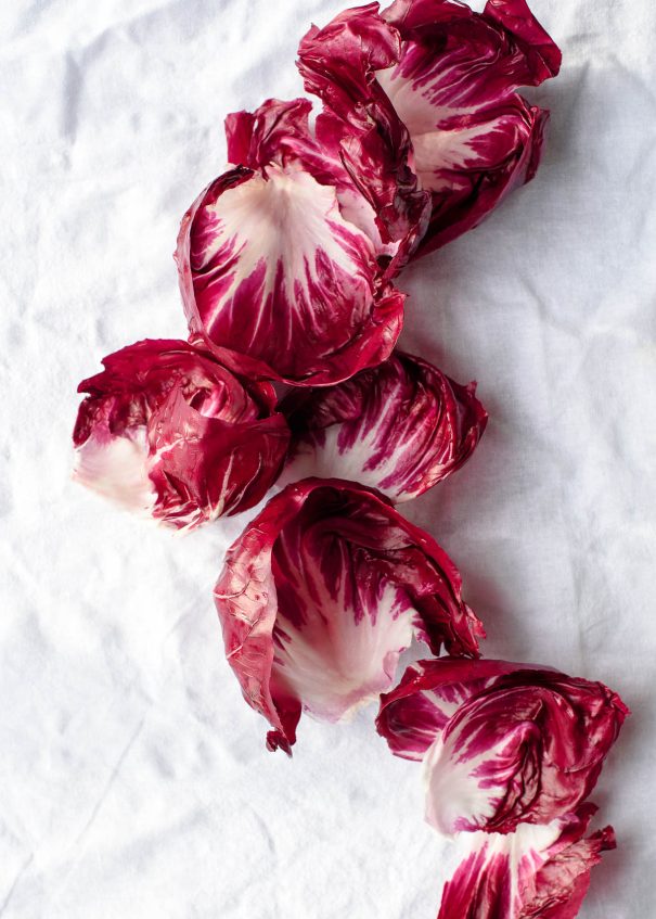 Fresh red and white radicchio leaves on a white linen tablecloth.