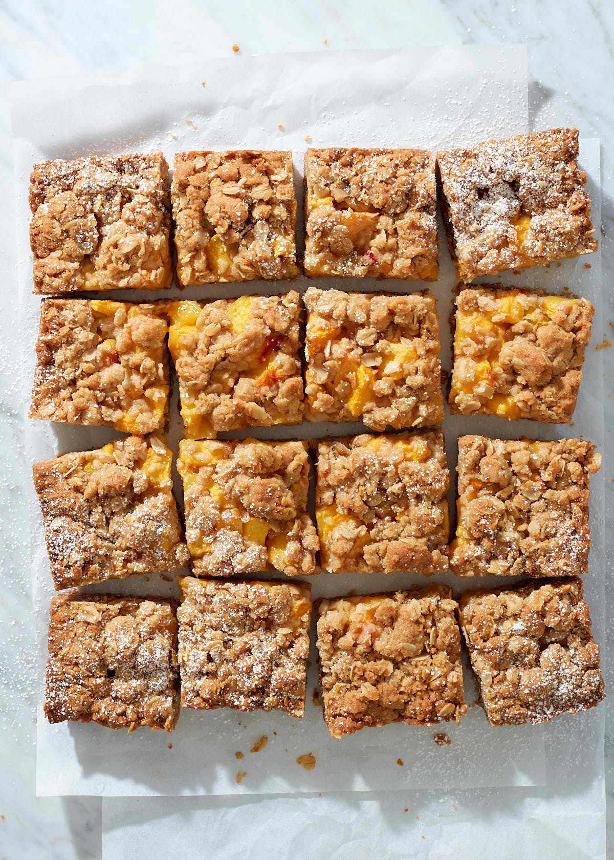 Peach bars sliced into equal sqaures on white parchment paper