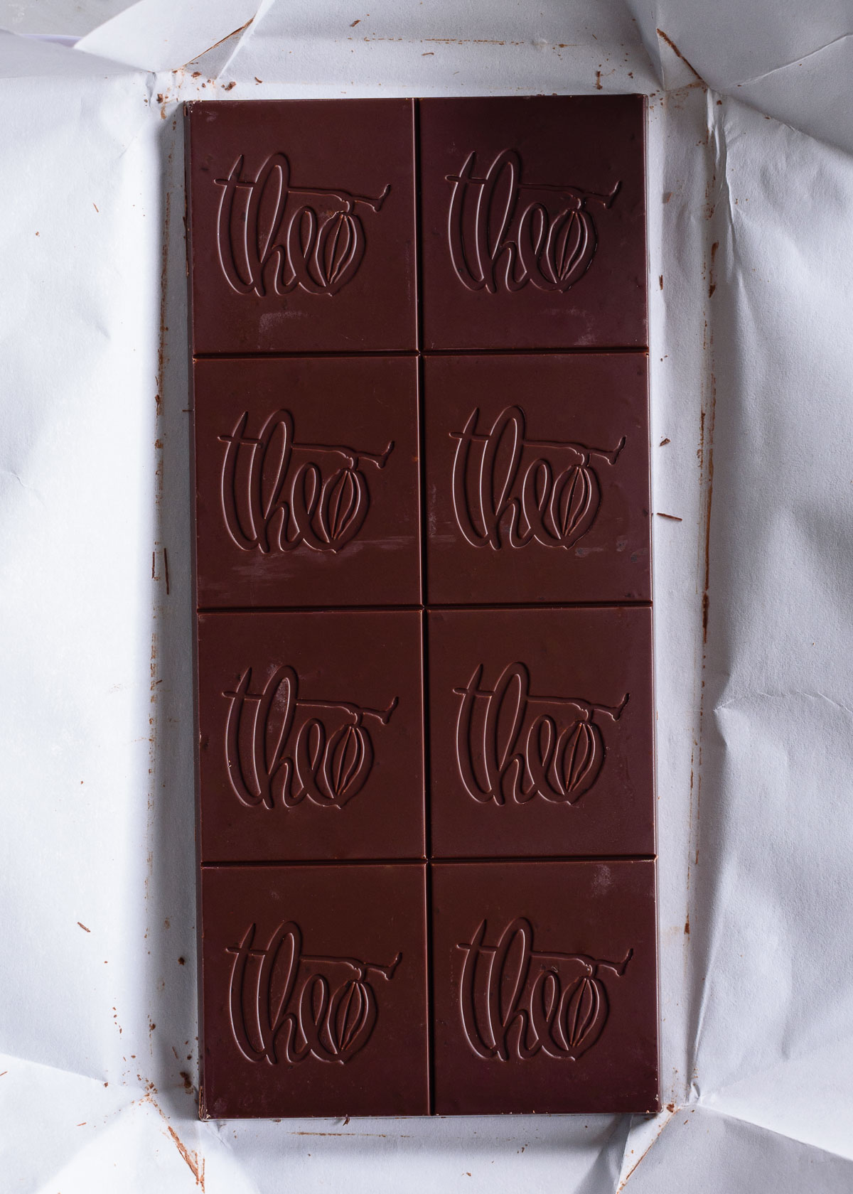 A close up of a dark chocolate baking bar from Theo Chocolate on top of a white wrapper.