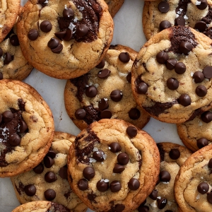 A pile of chocolate chip cookies on parchment paper.