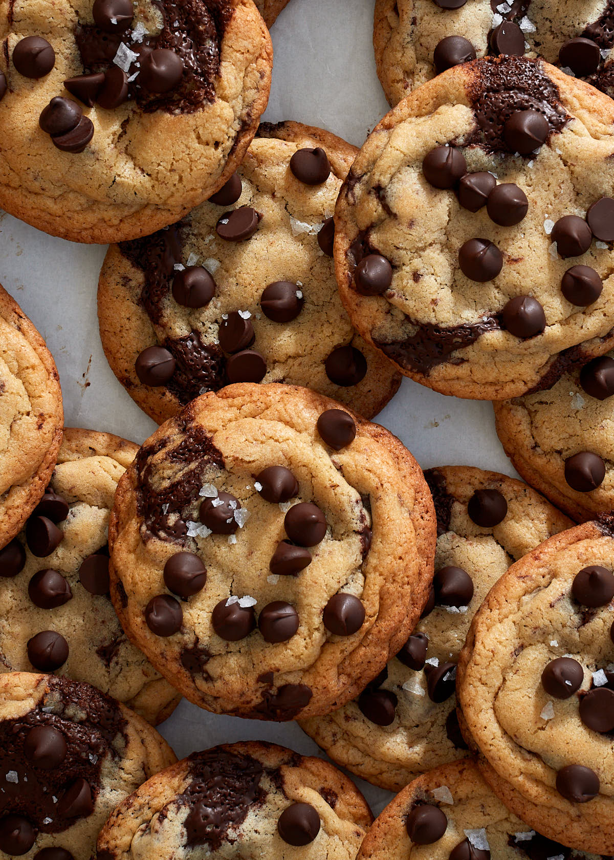 A pile of chocolate chip cookies on parchment paper.