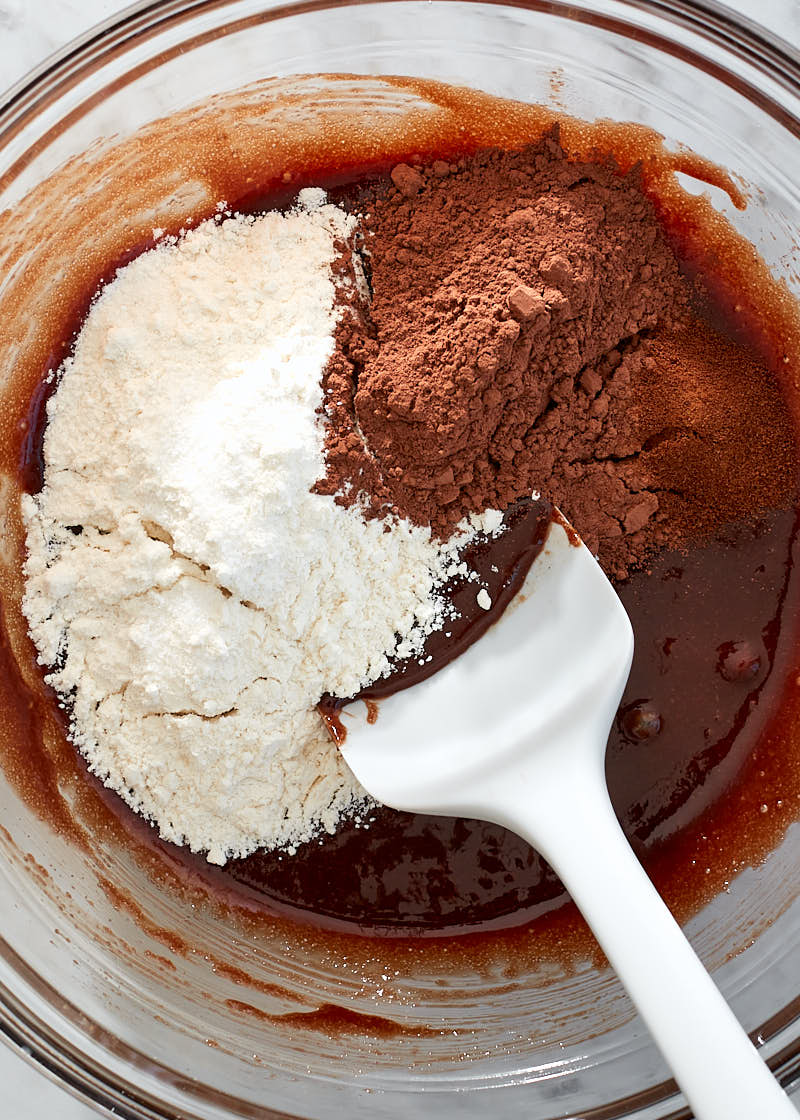 Closeup of flour and cocoa powder being added to brownie batter.