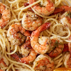 A close up of lemon shrimp pasta with bucatini, garlic, and herbs.