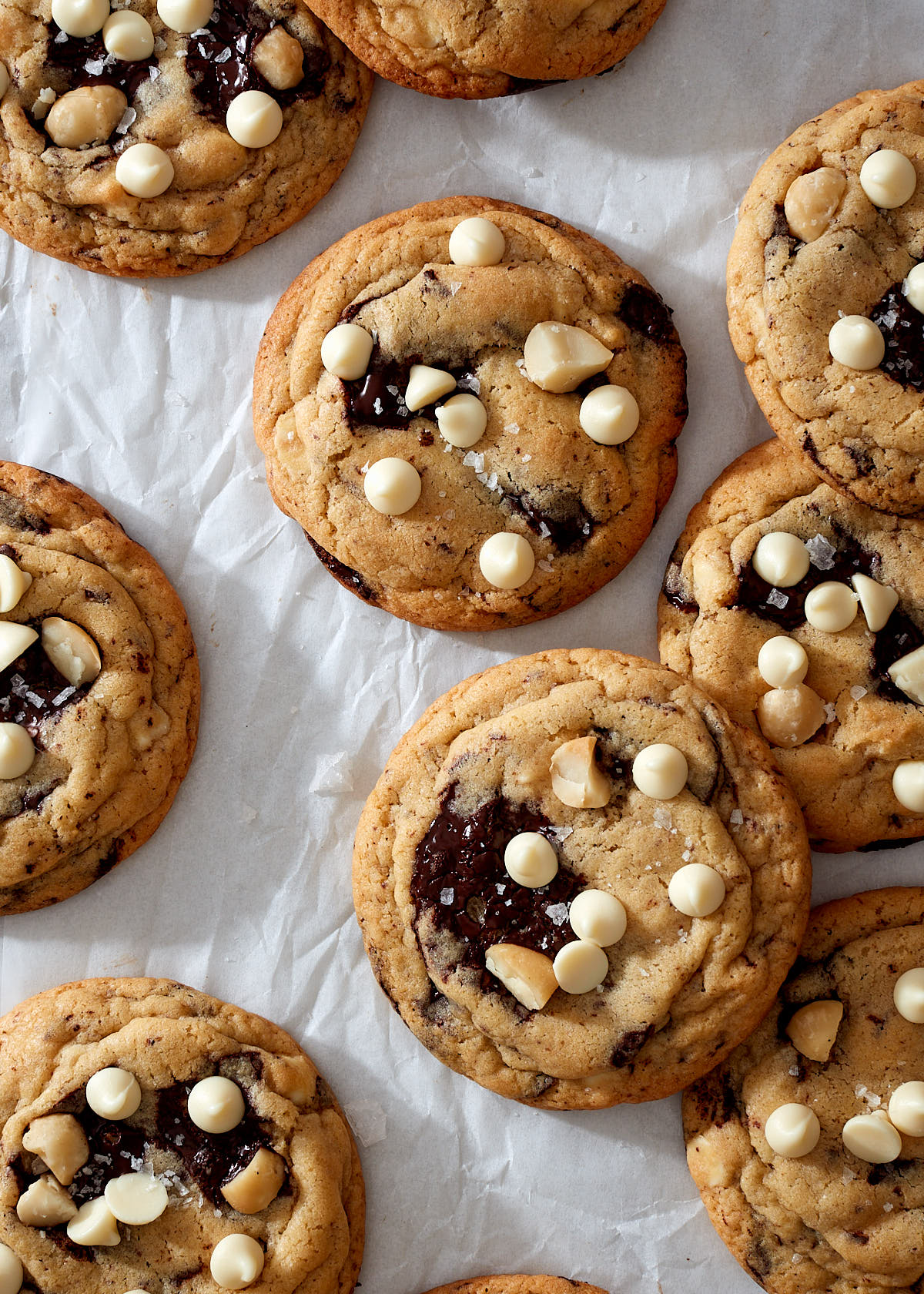 Chocolate macadamia nut cookies with dark and white chocolate chips on parchment paper.
