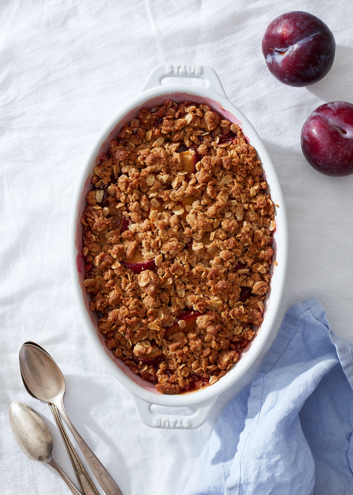 A plum crumble in a white baking dish.