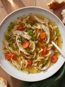 Homemade chicken noodle soup in a large bowl on a wooden table.