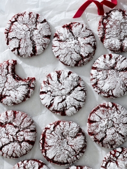 Red velvet crinkle cookies on white parchment paper.