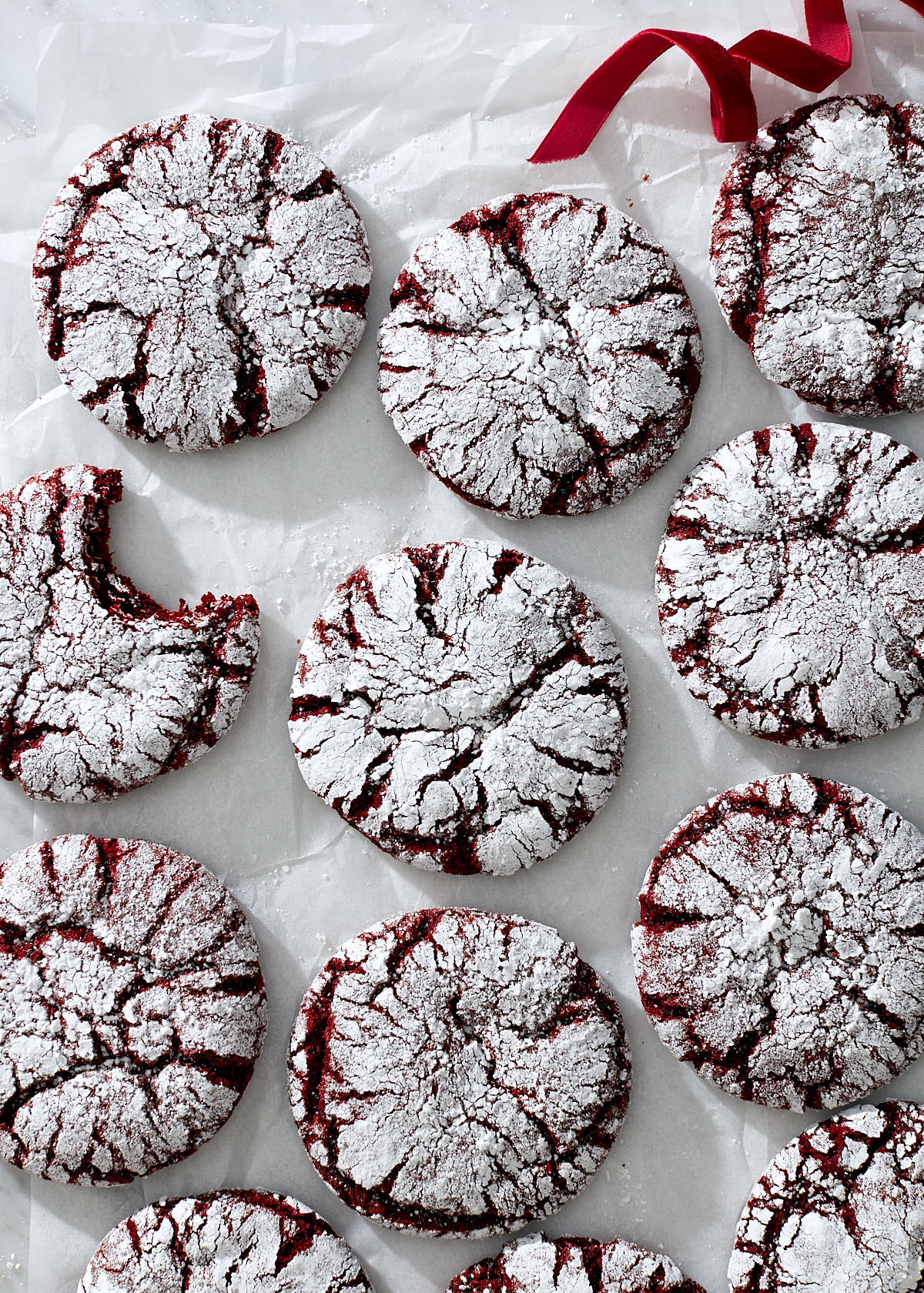 Red velvet crinkle cookies on white parchment paper.